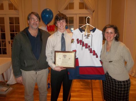 Noah Schultz (middle) holding his Hobey Baker plaque with his mom, Rebecca Schultz and his dad, Dan Schultz.