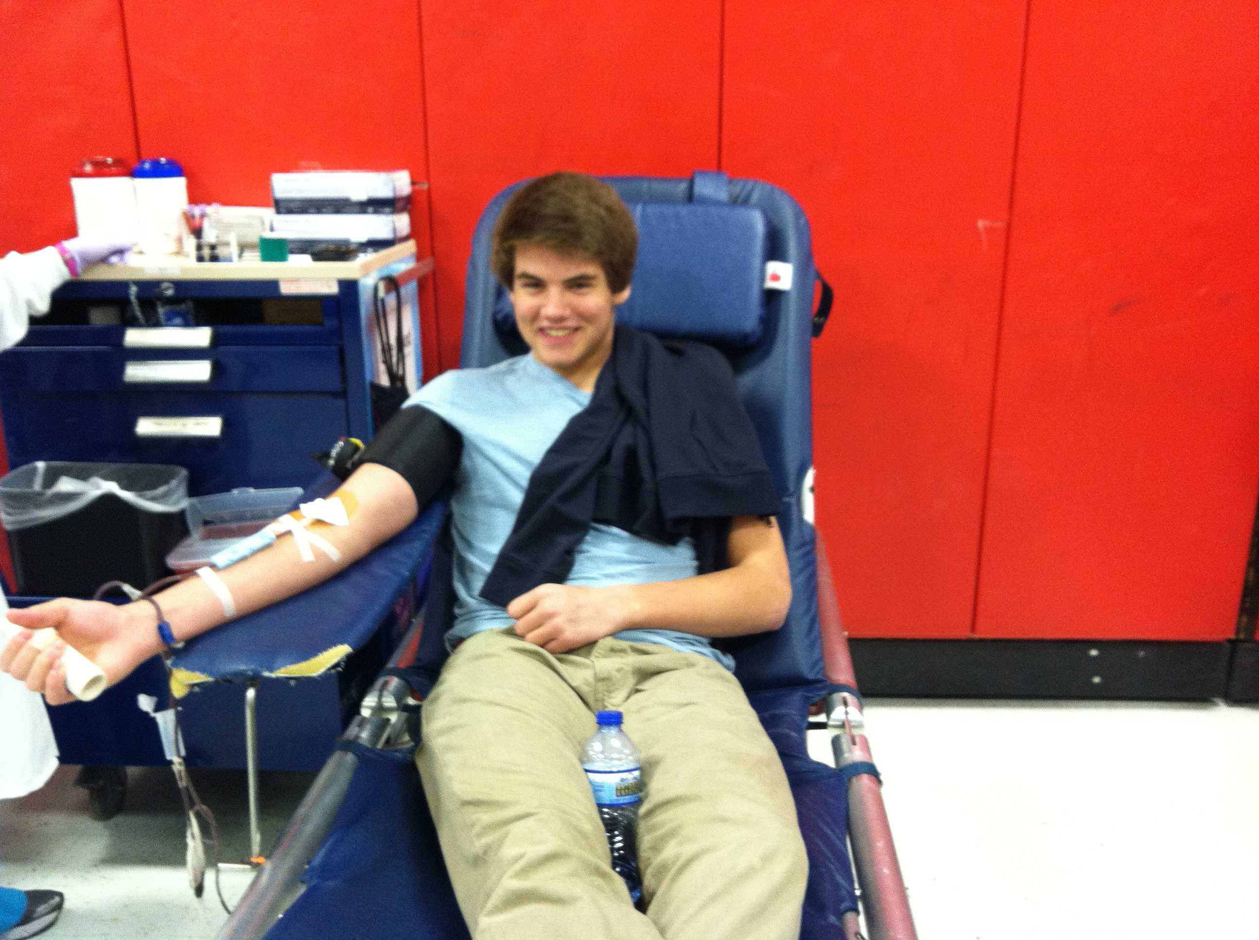 Senior Jake Anderson grins at the camera while giving blood.