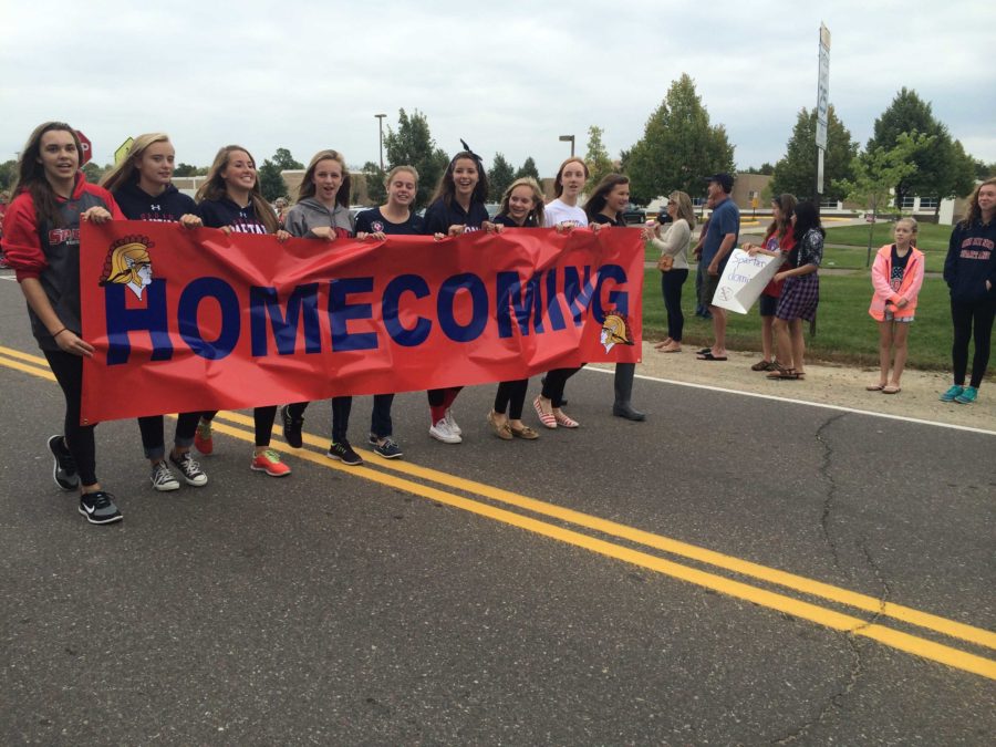 Sophomore girls walking the Homecoming banner down Old Crystal Bay Road.