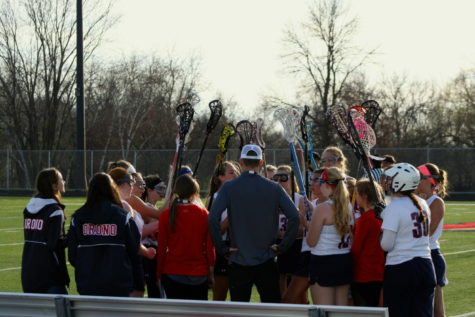 The girls lacrosse team huddles together.