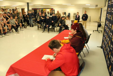 Friends and Family watch as student athletes sign their letters of intent