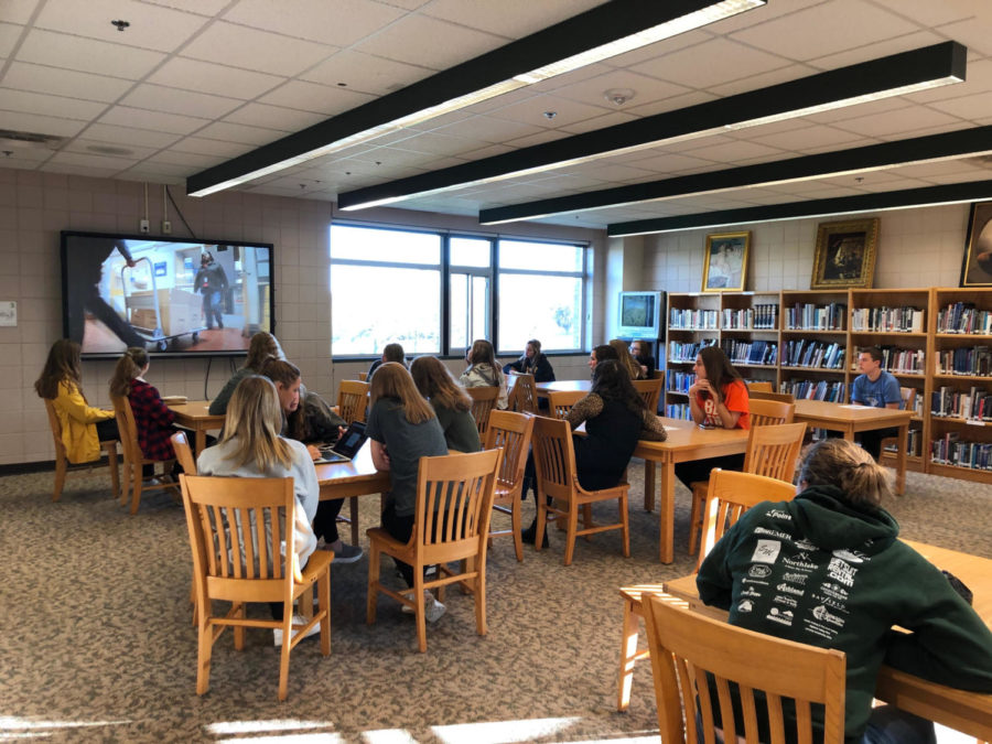 Youth in Action prepares for their upcoming food drive by watching an educational video.