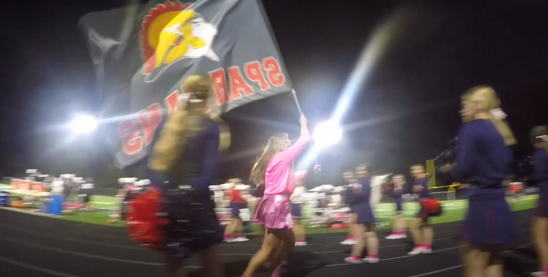 Megan Kostial runs through the Orono Cheerleaders waving the Spartans flag to rev. up the crowd.