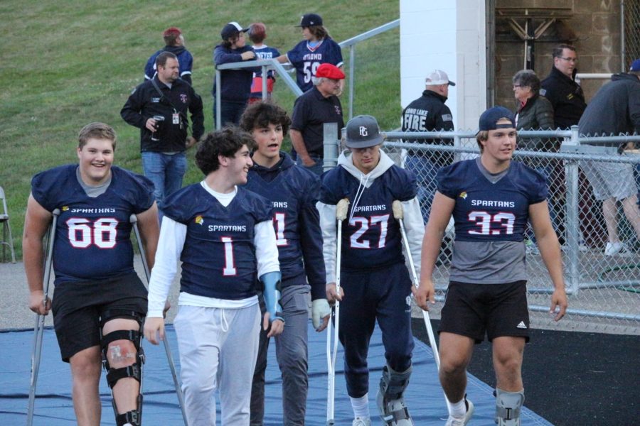 A group of injured football players walk out onto the field.