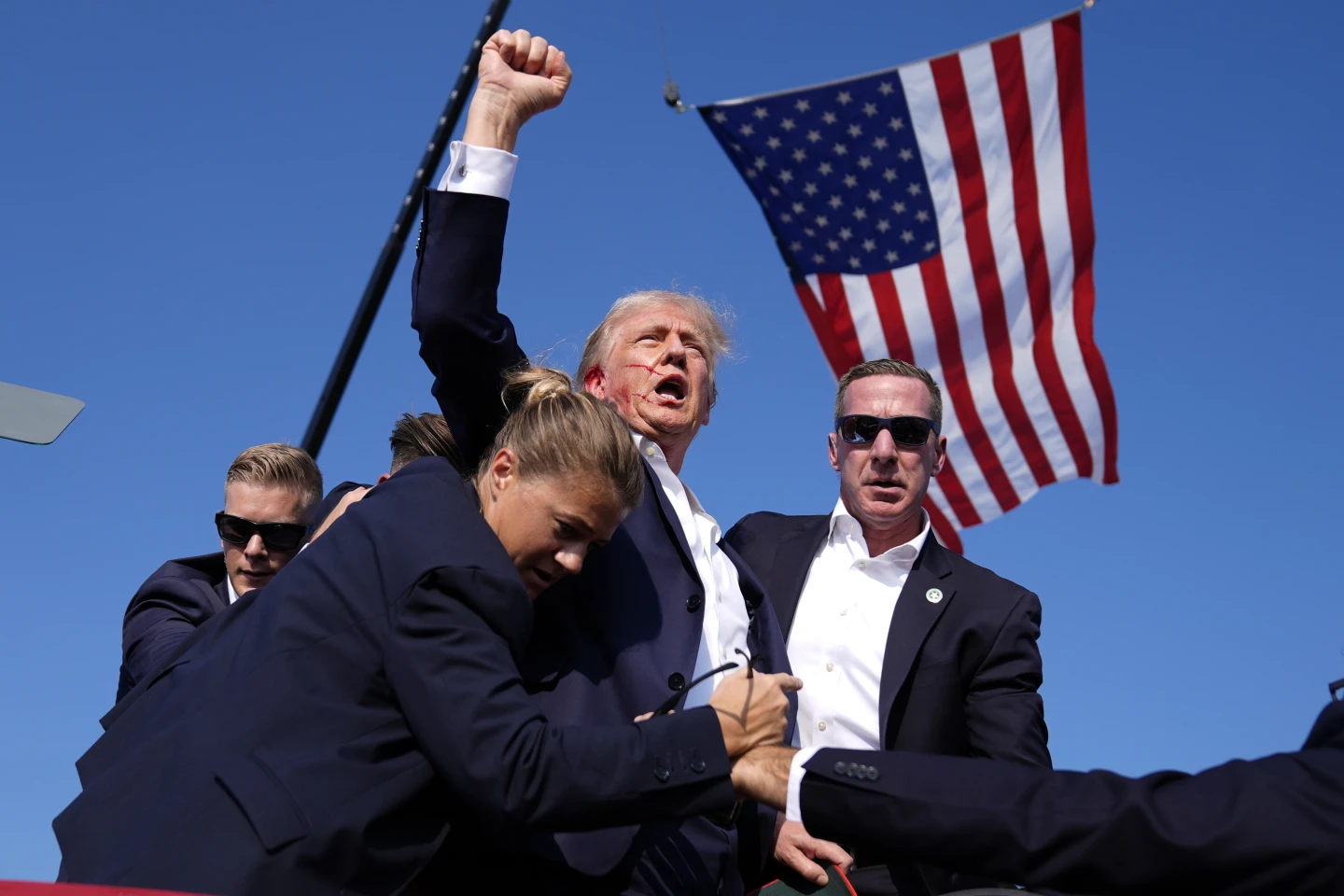 Former President Trump raising his fist after being shot in ear in assassination attempt.