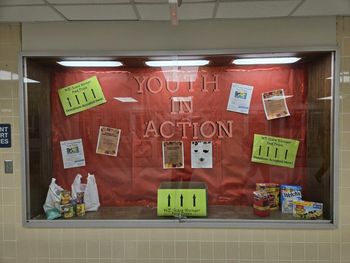 A Youth In Action display case with a "We Scare Hunger Food Drive" Box.