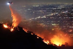 A helicopter douses the flames of the Los Angeles wildfires.